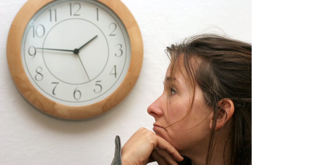 時計を見て待っている人の画像